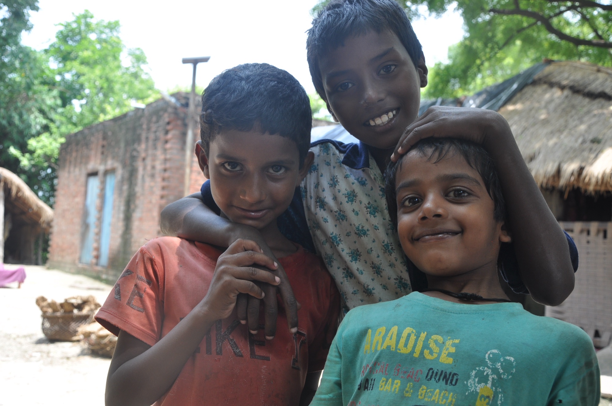Three boys from Masauli village smiling together in their neighbourhood